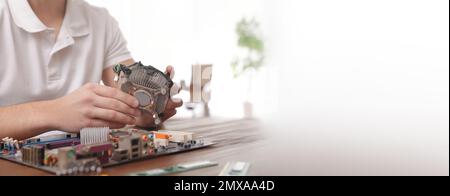 Male technician repairing computer at table indoors, space for text. Banner design Stock Photo