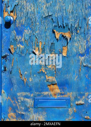 Blue paint peels from a wooden door. Stock Photo