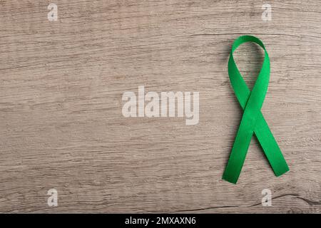Top view of emerald green ribbon on dark wood background. Liver