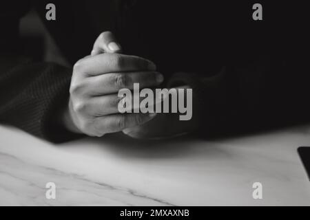 Tanned female hands holding hands in prayer. Copy space. Stock Photo