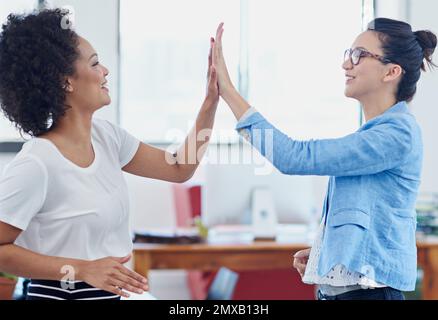 Way to go. two female coworkers high-fiving in an office. Stock Photo