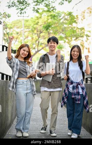 Group of cheerful young Asian college students showing fists, clenched fists, celebrating triumph, passing the exam, and enjoying university life. Stock Photo