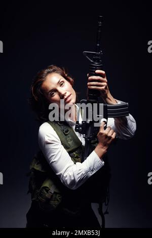 Powerful stance. Portrait of a woman wearing a safety jacket while standing and holding a rifle. Stock Photo