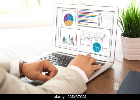 Value concept. Man working with laptop at table indoors, closeup Stock Photo