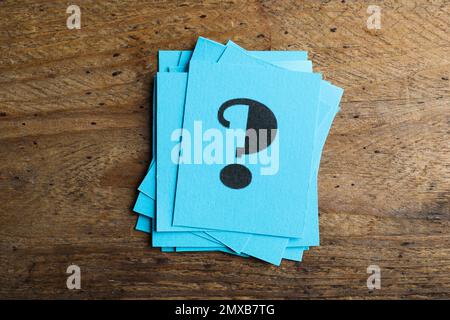 Blue paper cards with question mark on wooden background, top view Stock Photo