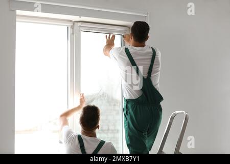 Professional workers tinting window with foil indoors Stock Photo