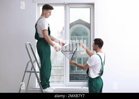 Professional workers tinting window with foil indoors Stock Photo