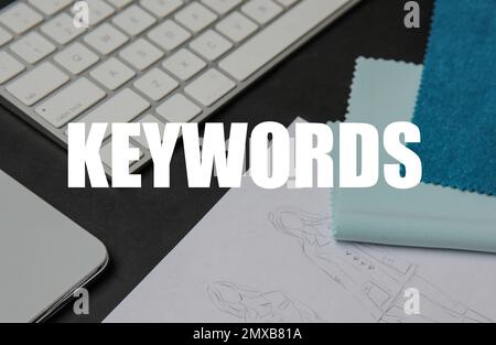 Text KEYWORDS, sketches and keyboard on dark background Stock Photo