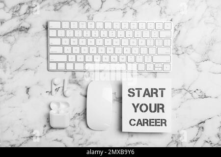 Flat lay composition with words START YOUR CAREER, computer keyboard, mouse and earphones on white marble table Stock Photo