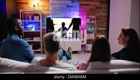 Couples Watching TV At Night. Television Screen Stock Photo