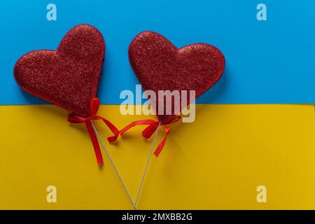 Two red hearts on blue and yellow color paper background for St Valentines day or 14 February, close up, top view, copy space Stock Photo