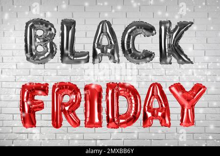 Phrase BLACK FRIDAY made of foil balloon letters against white brick wall Stock Photo