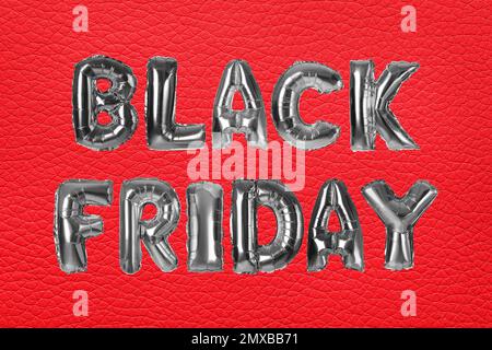 Phrase BLACK FRIDAY made of foil balloon letters on red background Stock Photo