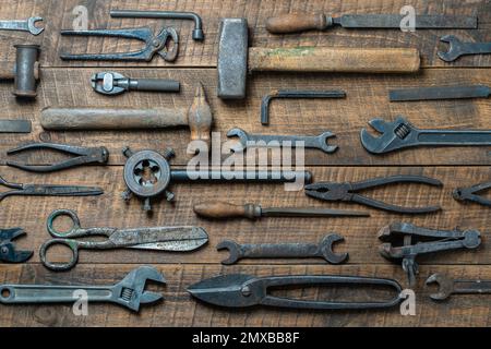 Vintage tools displayed on a background of wooden board, close up, top view. Dirty set old working tools Stock Photo