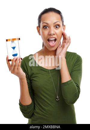 No time and so much to do. Portrait of a shocked looking young woman holding an hourglass isolated on white. Stock Photo