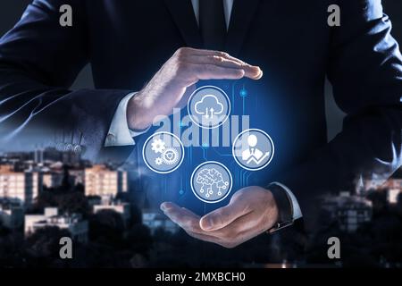 Man demonstrating machine learning model with different icons and night cityscape on background, closeup Stock Photo