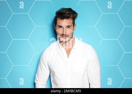 Facial recognition system. Young man with digital biometric grid on blue background Stock Photo