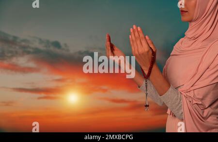 Muslim woman praying outdoors at sunset, closeup Stock Photo