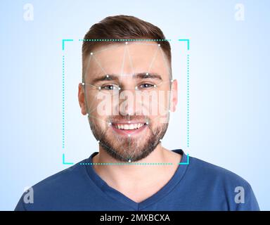 Facial recognition system. Young man with scanner frame and digital biometric grid on light background Stock Photo