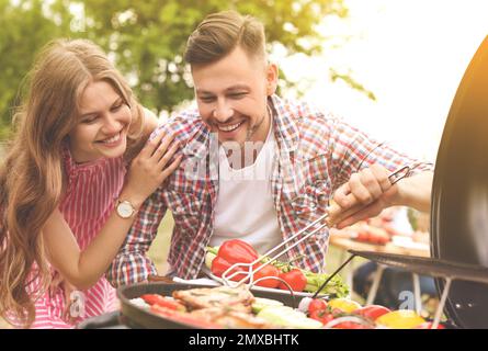 Young couple having barbecue with modern grill outdoors Stock Photo