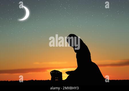 Silhouette of Muslim woman praying outdoors. Holy month of Ramadan Stock Photo