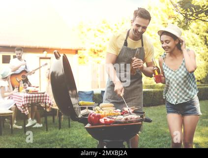 Young man and woman near barbecue grill outdoors on sunny day Stock Photo