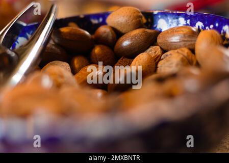 Close-up view of blue and white bowl of assorted nuts (hazelnuts, walnuts) with nutcracker in it Stock Photo