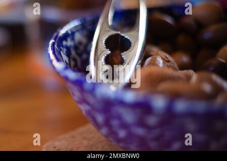 Close-up view of blue and white bowl of assorted nuts (hazelnuts, walnuts) with nutcracker in it Stock Photo