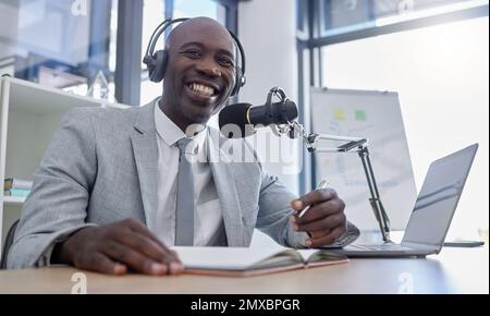 Portrait, microphone and man on laptop for radio, podcast or business influencer in studio, happy and excited. Face, talk show and host by black guy Stock Photo