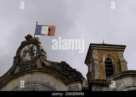 old winter town hall in cloudy grey sky in France with ancient vintage french flag Stock Photo
