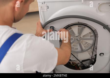 Professional plumber repairing broken washing machine, closeup Stock Photo