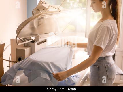 Woman using modern ironing press in dry-cleaning Stock Photo