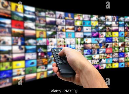 Streaming video services. Man using remote control to change channels on TV, closeup Stock Photo