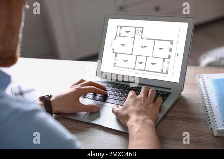 Architect making project of house on laptop at table indoors, closeup Stock Photo