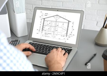 Architect making project of house on laptop in office, closeup Stock Photo