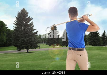 Young man playing golf on course with green grass, back view. Space for design Stock Photo