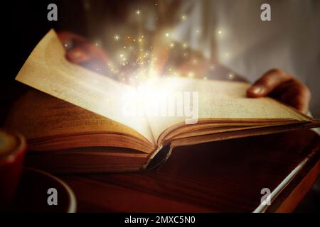 Woman reading shiny magic book, closeup view Stock Photo