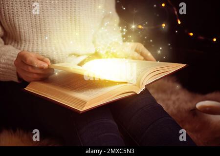 Woman reading shiny magic book, closeup view Stock Photo