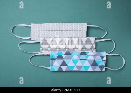 Homemade protective masks on blue-green background, flat lay. Sewing idea Stock Photo