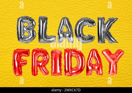 Phrase BLACK FRIDAY made of foil balloon letters on yellow background Stock Photo