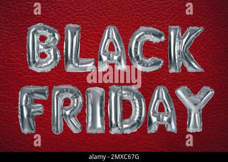 Phrase BLACK FRIDAY made of foil balloon letters on red background Stock Photo