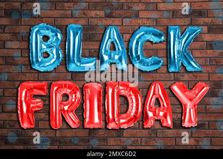 Phrase BLACK FRIDAY made of foil balloon letters against brick wall Stock Photo