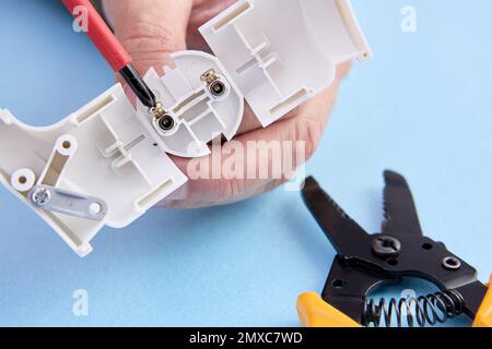 Collapsible electric plug of European standard type f, electrician mounts connector of electric cord. Stock Photo