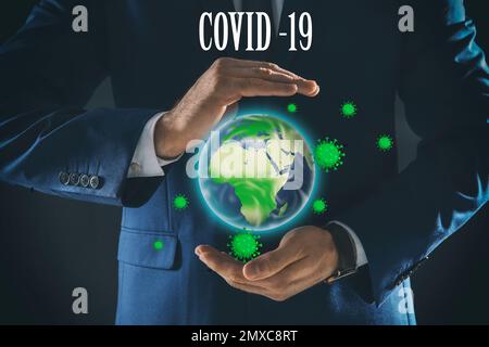 Corona crash. Businessman showing planet with virus on dark background, closeup Stock Photo