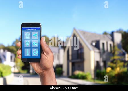 African-American man using home security app on smartphone outdoors, closeup. Space for text Stock Photo