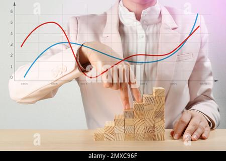 Finance trading concept. Woman with wooden blocks at table and chart, closeup Stock Photo