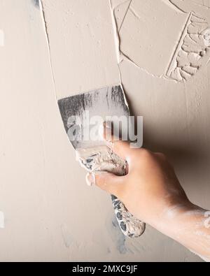 wall putty, spatula in hand closeup Stock Photo