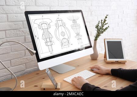 Male engineer working with technical drawing on computer indoors, closeup Stock Photo