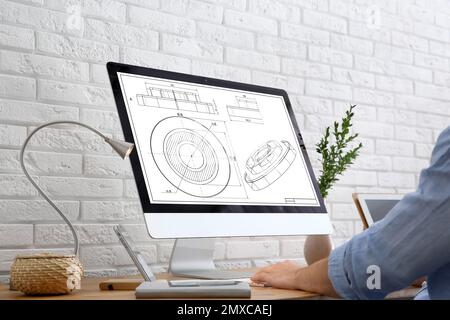 Male engineer working with technical drawing on computer indoors, closeup Stock Photo