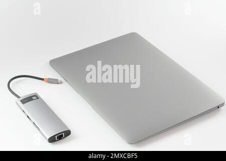 USB adapter connected to laptop with different inputs for flash drive, hdmi, ethernet, memory card, cables on white background. Stock Photo